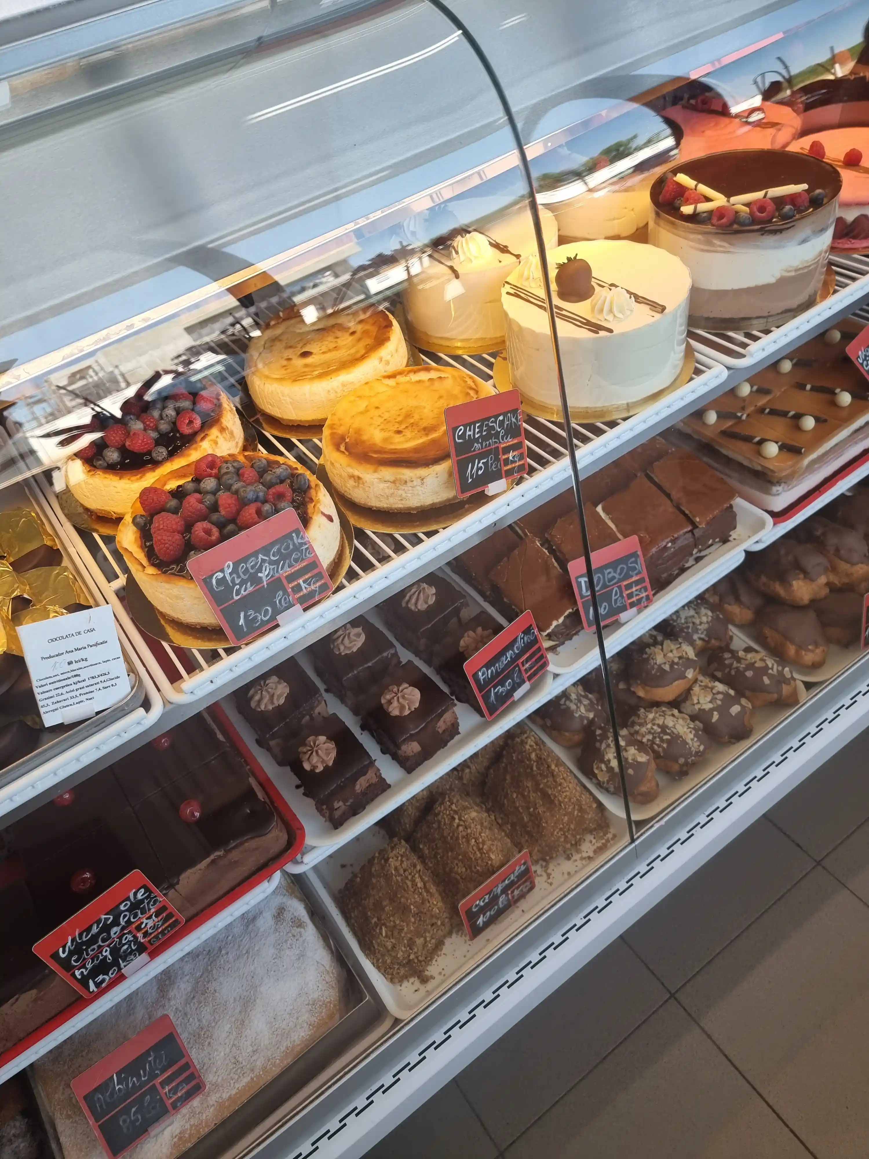 Vitrină cu torturi și prăjituri: cheesecake cu fructe de pădure, doboș și amandine